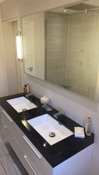 Double basin vanity unit with black worktop and wide wall mirror