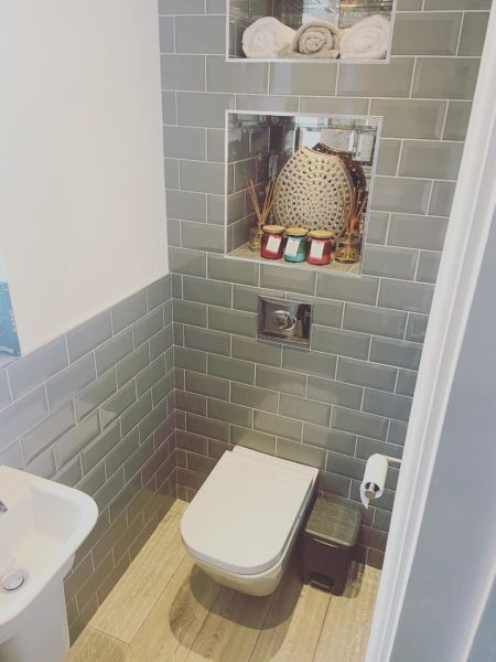 Wall-hung toilet with concealed cistern flush plate and tiled niche shelf