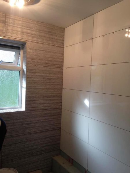 Shower area with large gloss wall panels and a woodgrain-effect feature wall
