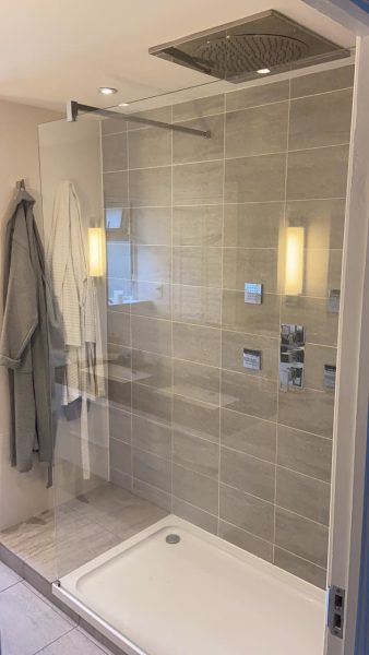 Walk-in shower with large-format wall tiles and chrome thermostatic shower controls